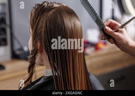 Beauty Master kämmt das nasse Haar des Kunden in Beauty Salon Nahaufnahme, Selbstpflegekonzept, professionelle Haarpflege Stockfoto