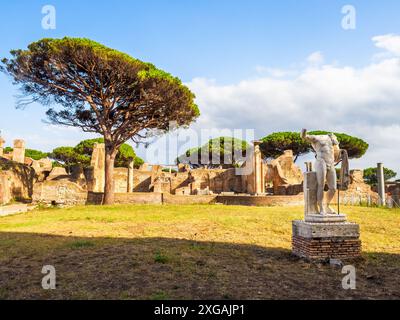 Foro della statua eroica – der Komplex wurde um 120 n. Chr. errichtet und war Sitz des Kollegiums der Fabri tignuarii, einer der bedeutendsten der Stadt. Im Innenhof stand eine Statue des Kaisers Septimius Severus (193–211 n. Chr.), auf dessen Basis die Namen der Mitglieder des Kollegiums - Archäologischer Park von Ostia Antica, Rom, Italien, eingetragen waren Stockfoto