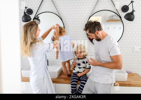 Eltern und Kinder, die morgens im Badezimmer sind, Zähne putzen und Gesicht waschen, genießen die gemeinsame Zeit. Stockfoto