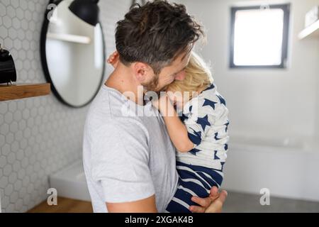 Dad und Junge haben morgens Badezimmerroutine, Zähne putzen und Gesicht waschen, gemeinsam Zeit genießen. Stockfoto