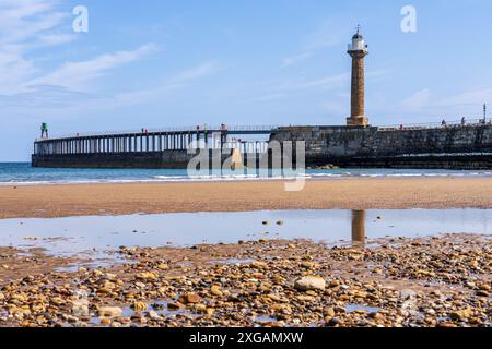 Whitby, North Yorkshire, England, Großbritannien - 21. Juni 2023: Whitby Harbour West Lighthouse und West Pier, vom Strand aus gesehen Stockfoto