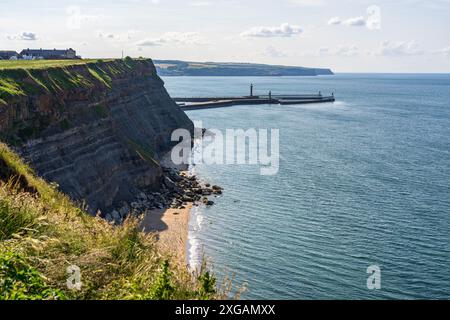 Whitby, North Yorkshire, England, Großbritannien - 21. Juni 2023: Blick über die Nordseeküste und den Pier von den Klippen Stockfoto