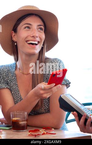 Junge Frauen zahlen kontaktlos über die Handy-App im Restaurant Stockfoto