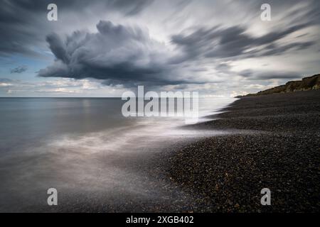 Eine Sturmwolke zieht über den Kieselstrand am Weyborne Beach, Norfolk. Stockfoto