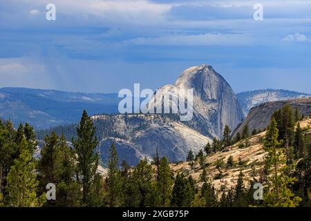 Die Sonne bricht durch die Wolken und beleuchtet Half Dome, eine berühmte Granitfelsenformation im Yosemite Valley, Yosemite National Park, Kalifornien, USA. Stockfoto