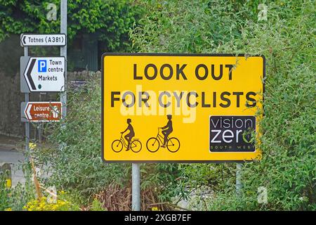 Halten Sie Ausschau nach Radfahrern. Ein deutliches gelbes Straßenschild an der Kreuzung des Kreisverkehrs ist ein multinationales Projekt der Vision Zero zur Verkehrssicherheit in England Großbritannien Stockfoto