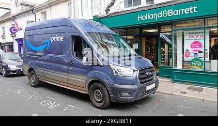 Front- und Seitenansicht des Ford Transit Pakettransporters mit Amazon Prime Markenlogo außerhalb von Holland und Barrett Fahrer macht Paketzustellung UK Stockfoto