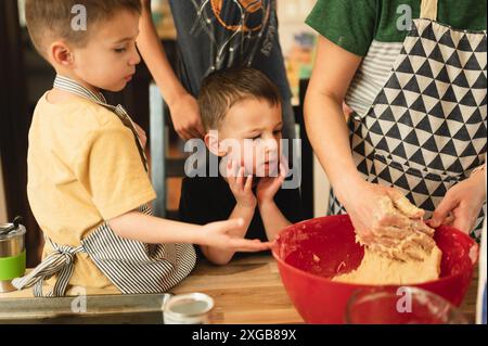 Junge Geschwister, die darauf warten, dass Mom mit dem Keksenteig fertig ist Stockfoto