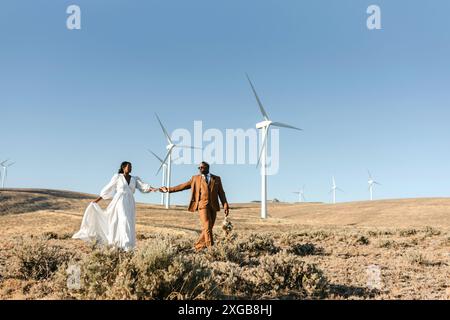 Mann und Frau gehen auf einem Hügel auf einer Solarwindkraftanlage Stockfoto