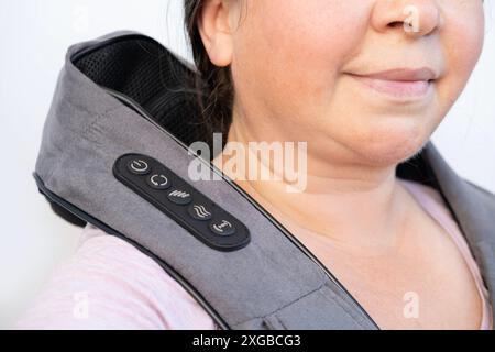 Ältere Weiße 55er Jahre mit tragbarem Elektromassagegerät, therapeutischer Entspannung von Trapez, Kugelvibrationsmassagegerät für den Hals liegt auf der Frau Stockfoto