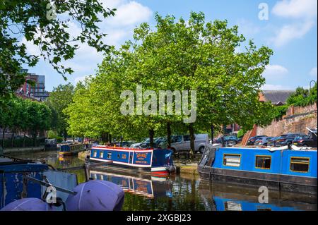 Schwarzkahn, Liftbrücke und Bäume im Castlefield Bridgewater Canal Basin, Manchester, Großbritannien, an einem sonnigen Juni-Tag mit blauem Himmel. Stockfoto