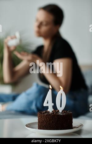 Frau, die neben einer 40. Geburtstagstorte auf einem Bett sitzt. Stockfoto