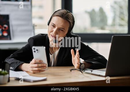 Frau mittleren Alters im Headset, die am Schreibtisch sitzt und telefoniert. Stockfoto
