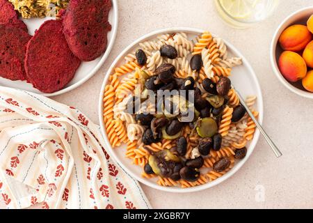 Genießen Sie ein köstliches vegetarisches Gericht mit glutenfreier Pasta mit gebackenen Bohnen und Zucchini, begleitet von Rübenpfannkuchen mit Sonnenblumenkorn-Hummus. Ein Vorteil Stockfoto