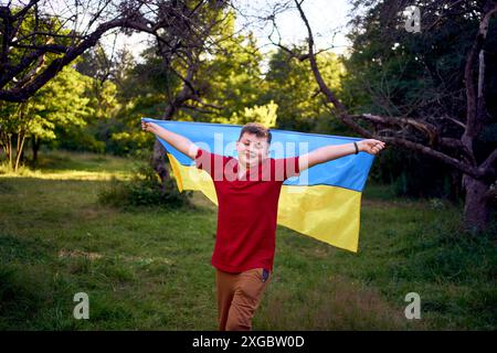 Preteen Boy läuft im Park mit der Flagge der Ukraine Stockfoto