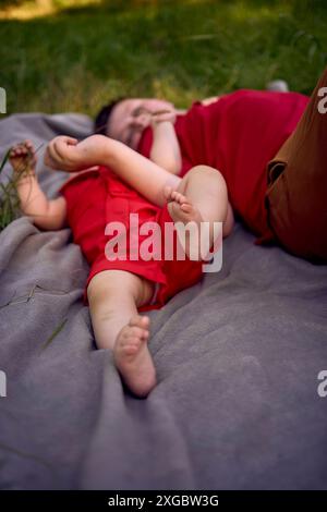 Baby und ihr großer Bruder liegen auf einer Decke im Park Stockfoto