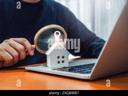 Online-Wohnungssuche, Immobilienwert, Immobilienkauf und -Verkauf, Immobilieninvestitionskonzepte. Pointer-Symbol auf dem weißen Haus auf dem Laptop Stockfoto