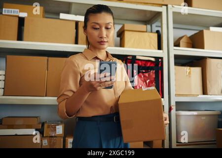 Frau, Die Auf Dem Smartphone Paketdienste Online Überprüft Stockfoto