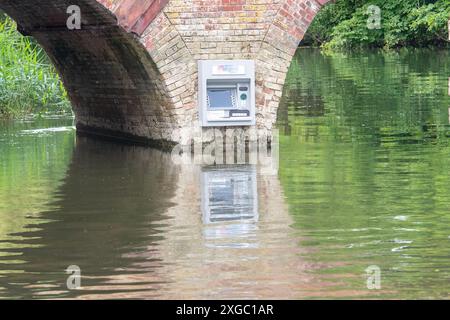 Sonning-on-Thames, Berkshire, Großbritannien. Juli 2024. Ein Streich namens Impro hat an der Wand der Sonning Bridge oberhalb der Themse in Sonning-on-Thames, Berkshire, einen Geldpunkt platziert. Über dem Cashpoint befindet sich ein Impro Solutions Logo. Impro war auch hinter einem Briefkasten, der vor ein paar Monaten an derselben Mauer über der Themse angebracht wurde. Dies hat den Einheimischen viel Spaß bereitet und das Ziel soll darin bestehen, die Aufmerksamkeit auf die Anzahl der Banken zu lenken, die geschlossen werden. Berühmte Bewohner, die Eigentum in Sonning besitzen, sollen George Clooney und der ehemalige P sein Stockfoto