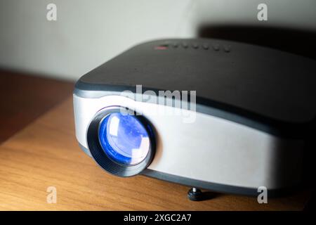 Nahaufnahme eines modernen Projektors mit blauer Linse auf Holzoberfläche. Stockfoto