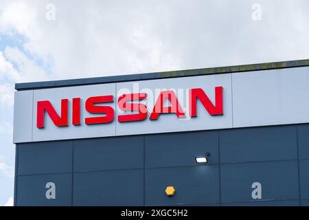 Telford, Großbritannien - 8. Juli 2024: Name des Motorunternehmens Nissan außerhalb eines Ausstellungsraums eines Autohändlers Stockfoto