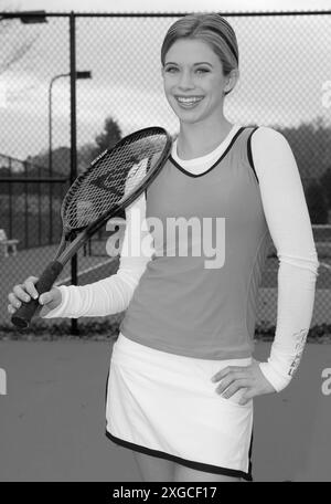 Kaukasisches Teenager-Mädchen lächelt, während er in den USA einen Tennisschläger hält. Stockfoto