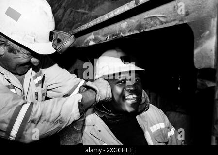 Eine Großaufnahme der Graustufen zweier afrikanischer Arbeiter, die sich im Untergrund Platinum Palladium Mining and Machinery in Johannesburg, Südafrika, amüsieren Stockfoto