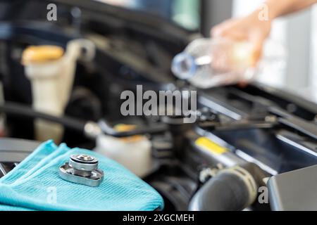 Eine Frau nimmt die Sache selbst in die Hand, Kühlernachfüllung. Mechaniker, der Automotorreparaturen in einer Autowerkstatt durchführt. Eine Nahaufnahme einer Hand Stockfoto