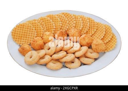 Verschiedene Kuchen und Waffeln in Keramikplatte isoliert auf weißem Hintergrund. Goldener romantischer Keks. Draufsicht. Stockfoto