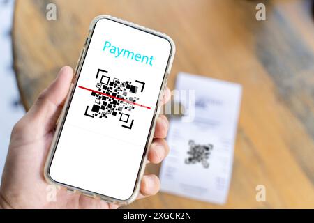 Männliche Hand, die ein Smartphone mit qr-Code auf dem Bildschirm hält. Scannen des qr-Codes. Strichcode-Lesegerät. Bargeldlose Technologie, Digital Money Concept. Stockfoto