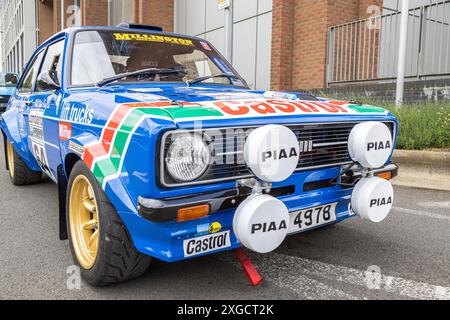 Ein Ford Escort Rallyefahrzeug mit vollem Aufkleber, der in einer städtischen Umgebung auf der Straße geparkt ist. Stockfoto