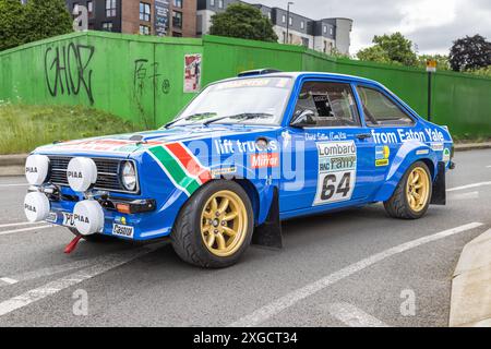 Ein Ford Escort Rallyefahrzeug mit vollem Aufkleber, der in einer städtischen Umgebung auf der Straße geparkt ist. Stockfoto