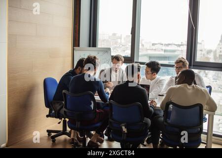 Startup-Unternehmen, junge kreative, multiethnische Geschäftsleute treffen sich im Tagungsraum mit Panoramafenster und moderner Büroeinrichtung Stockfoto