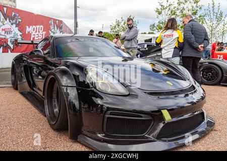 Dreiviertelansicht eines Porsche Cayman mit Karosserie-Styling-Kit, der während des Coventry Motofests in einer urbanen Umgebung geparkt wurde. Stockfoto