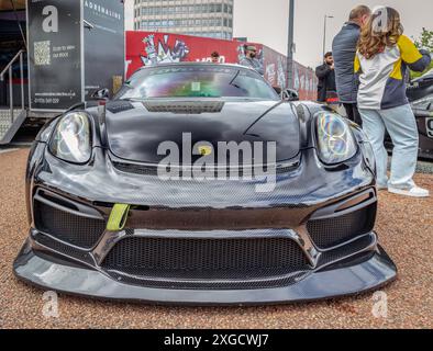 Vorderansicht eines Porsche Cayman mit Karosserie-Styling-Kit, der während des Coventry Motofests in einer urbanen Umgebung geparkt wurde. Stockfoto