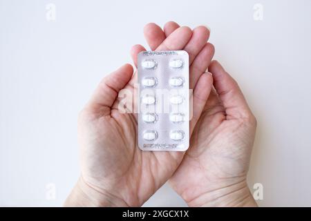 Menschliche Hände, die medizinische Kapseln in Blisterpackung halten. Kaukasier, der Arzneimittel in der Hand hält. Gesundheitskonzept. Stockfoto