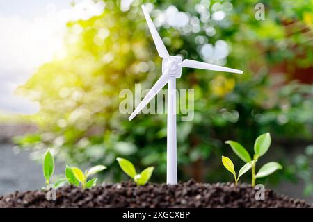 Die Sapling wachsen aus dem Boden mit einer Windkraftanlage auf blauem Himmel. Energie sauberer Strom, erneuerbare Energien. Stockfoto