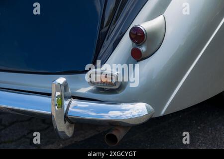 Eine Nahaufnahme des hinteren Stoßfängers und der Rückleuchten eines Oldtimers. Das Auto ist blau und silber lackiert, und der Stoßfänger ist verchromt. Die Schlussleuchten sind r Stockfoto