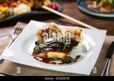 Gegrilltes Lachssteak garniert mit Sauce und Kräutern serviert Stockfoto
