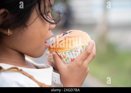 Ein Kind, das draußen einen Cupcake hält und isst. Stockfoto