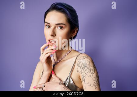 Eine Frau, die mit Tätowierungen auf Armen und Brust geschmückt ist, strahlt Selbstvertrauen und Individualität in einem Studio aus. Stockfoto