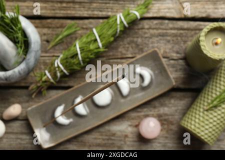 Flache Lagenkomposition mit Räucherstäbchen schwelend in Halter auf Holztisch Stockfoto