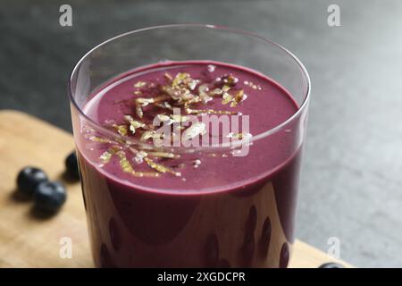 Leckerer frischer Acai-Saft mit Zitronenschale im Glas auf grauem Tisch, Nahaufnahme Stockfoto