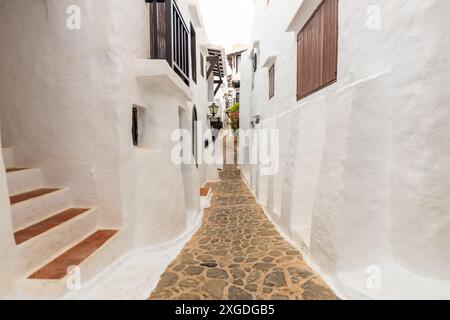 Die wunderschöne Stadt Binibeca auf Menorca. Enge Gassen und weiße Wände von Häusern mit Holzelementen, mediterrane Architektur in Spanien Stockfoto