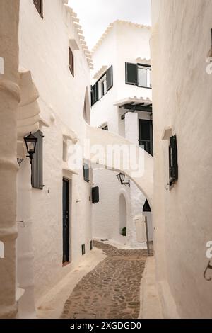 Die wunderschöne Stadt Binibeca auf Menorca. Enge Gassen und weiße Wände von Häusern mit Holzelementen, mediterrane Architektur in Spanien Stockfoto