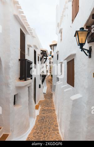 Enge Gassen des wunderschönen Dorfes Binibeca auf Menorca. Weiße verputzte Hauswände mit Holzelementen. Eine charmante Stadt in Spanien am Bale Stockfoto