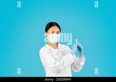 Frau im Gesundheitswesen, die Spritze vor blauem Hintergrund hält Stockfoto