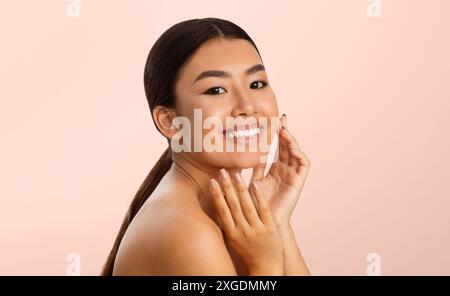 Glückliche Junge Frau Mit Langen Braunen Haaren, Die Ihr Gesicht Berühren Stockfoto