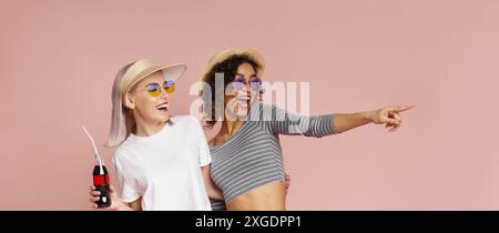 Zwei Frauen Lachen Zusammen In Sommeroutfits Vor Rosafarbenem Hintergrund Stockfoto