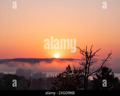 Mittsommer Sonnenaufgang über dem Fluss in Skandinavien mit Nebel Stockfoto